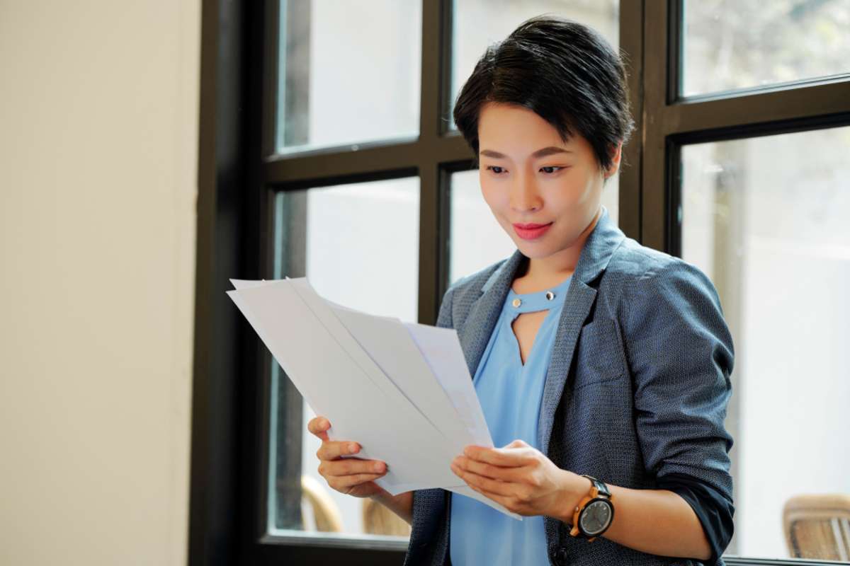 Asian young female executive reading a documents in her hands while working at office