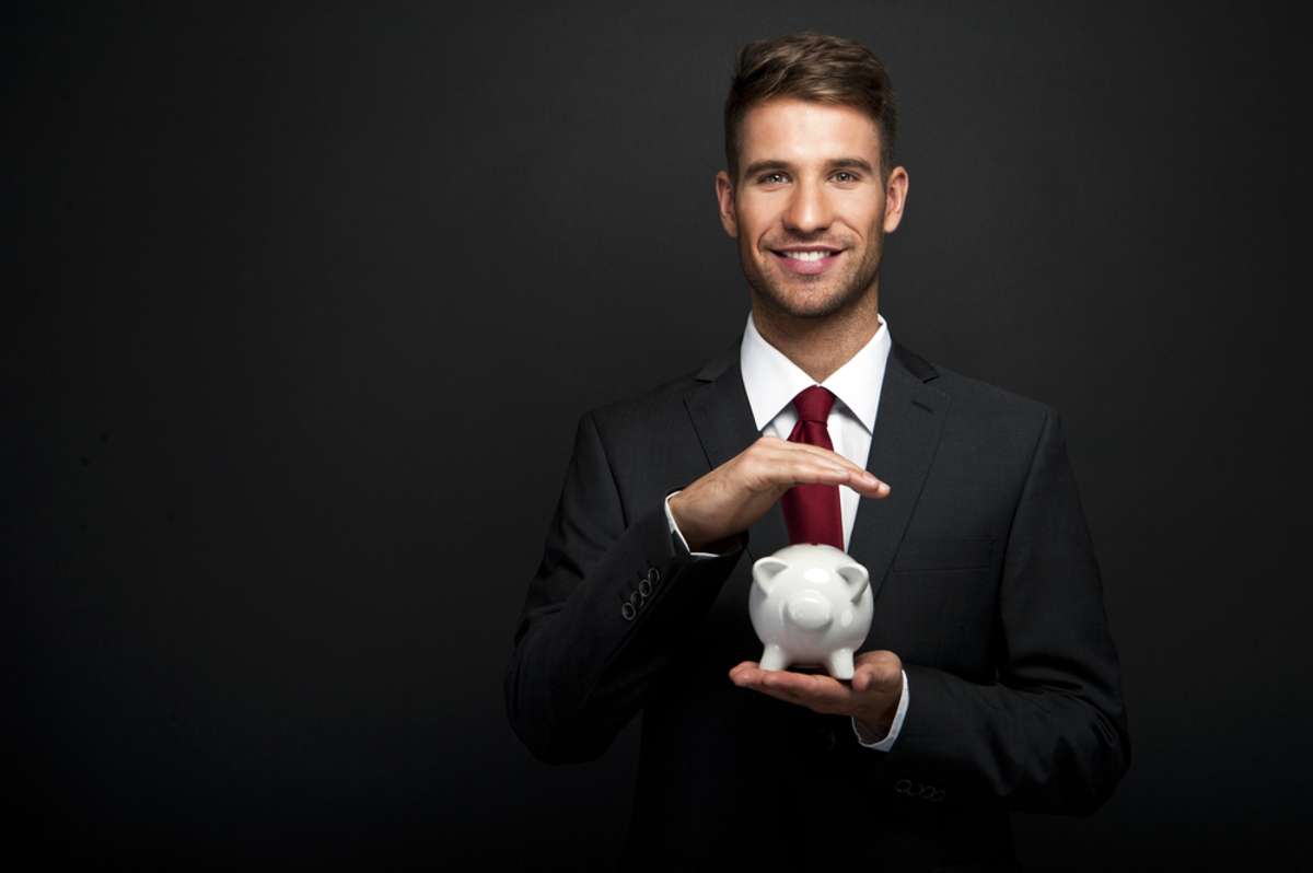 Businessman with piggy bank over dark background