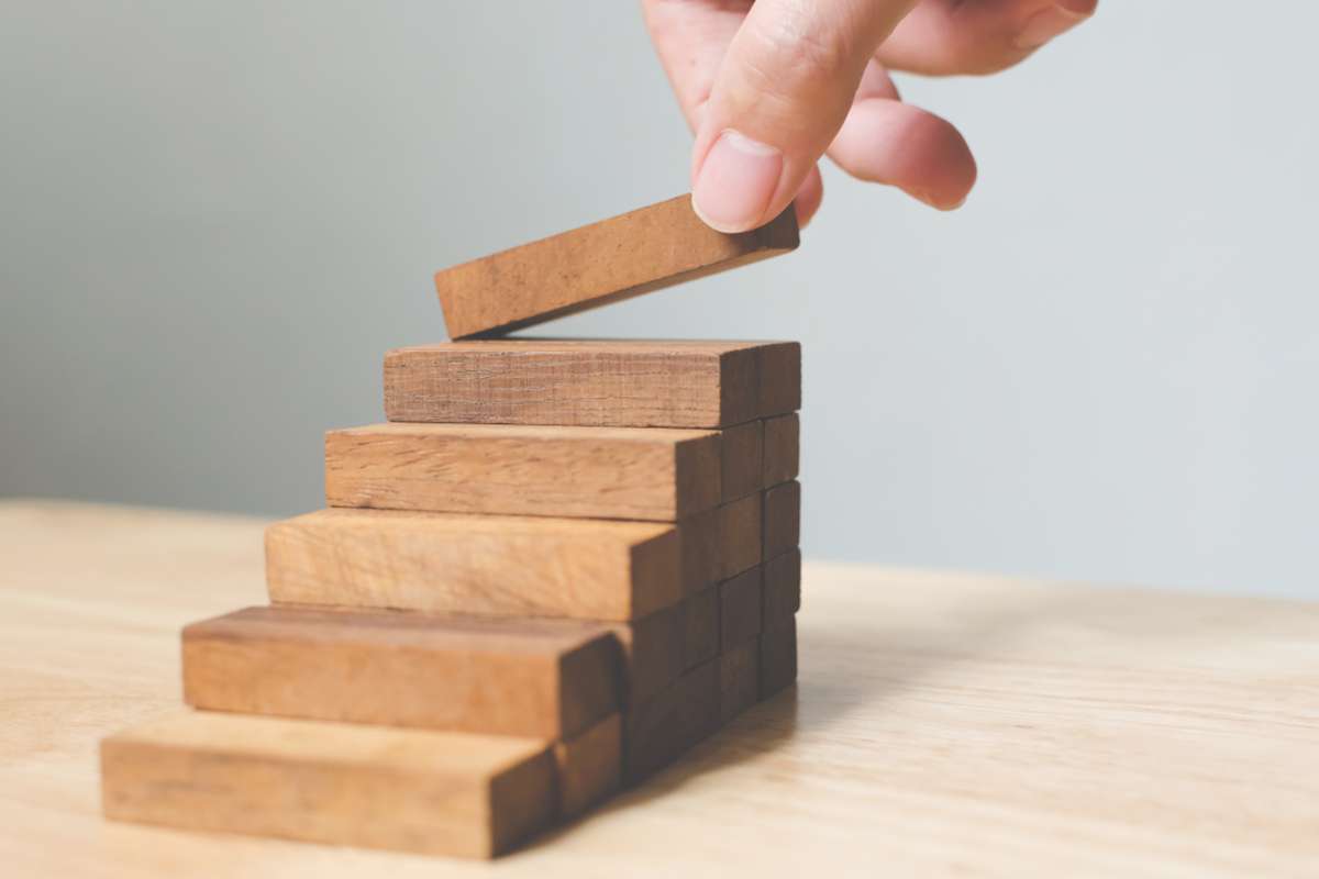 Hand arranging wood block stacking as step stair