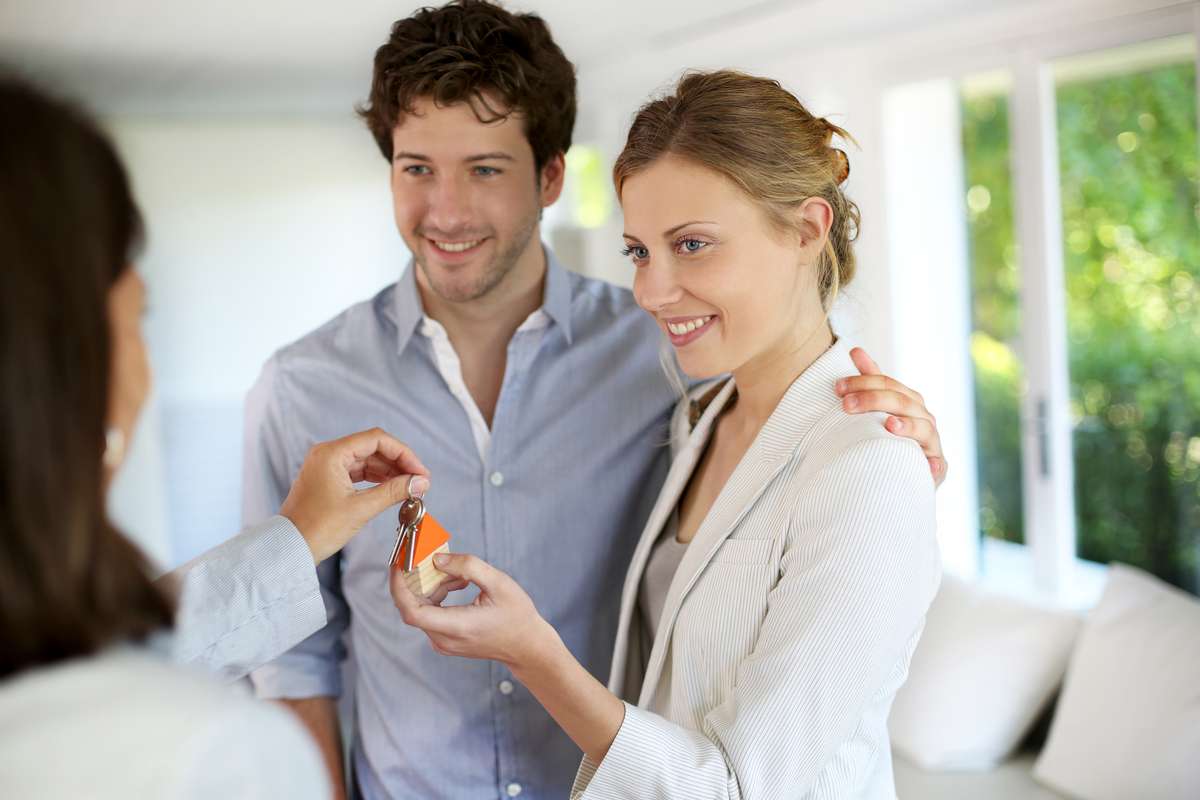 Happy young couple getting keys of their new home (R) (S)
