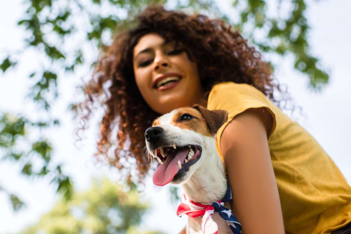 Selective focus of excited, curly woman holding jack russell terrier dog, low angle view (R) (S)