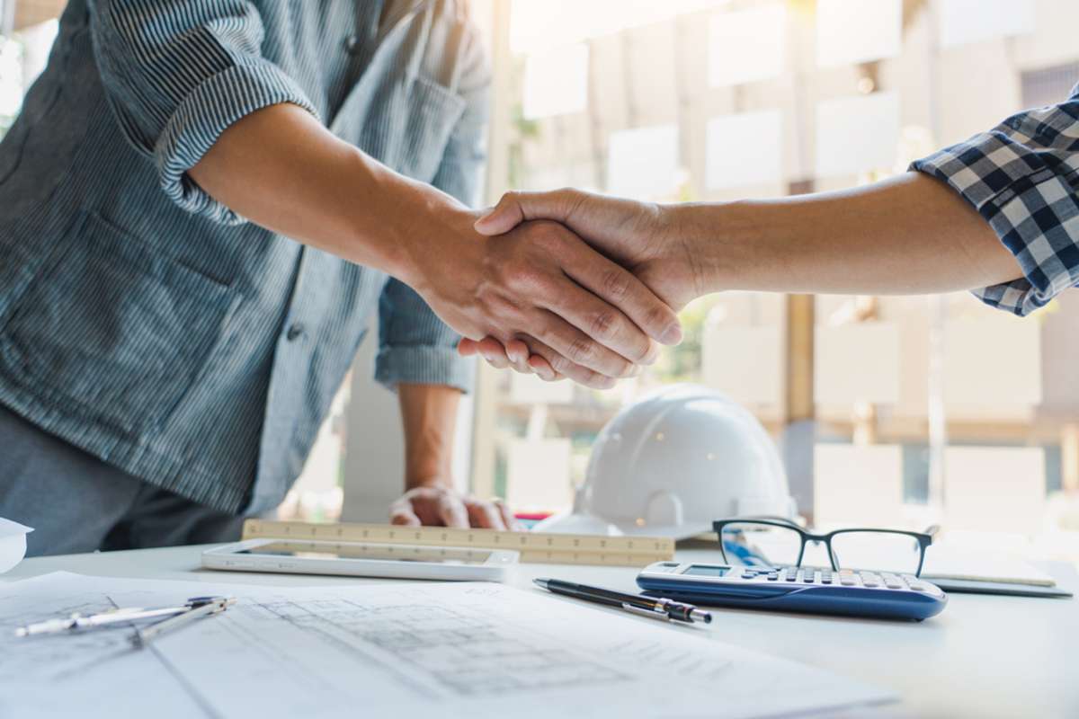 Architect and engineer construction workers shaking hands while working for teamwork and cooperation